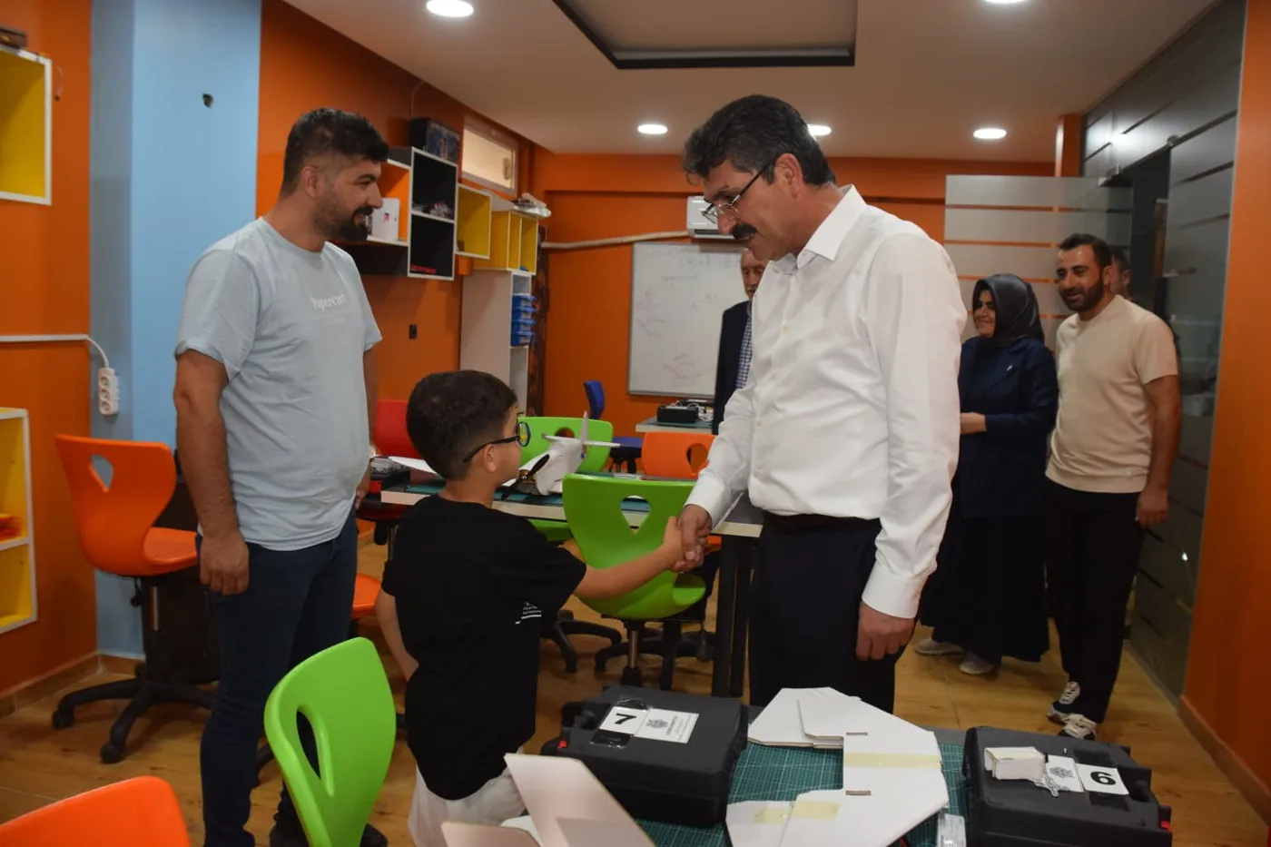Batman Milletvekili Ferhat Nasıroğlu, CEZERİ ROBOTECH atölyesinde model uçak yapan bir öğrenciyle tokalaşıyor