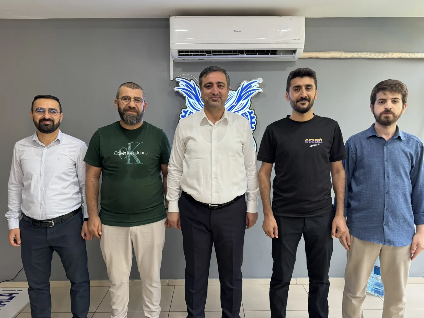 Batman Milletvekili Serkan Ramanlı ve CEZERİ ROBOTECH ekibi, kurumun robotik baykuş amblemi önünde